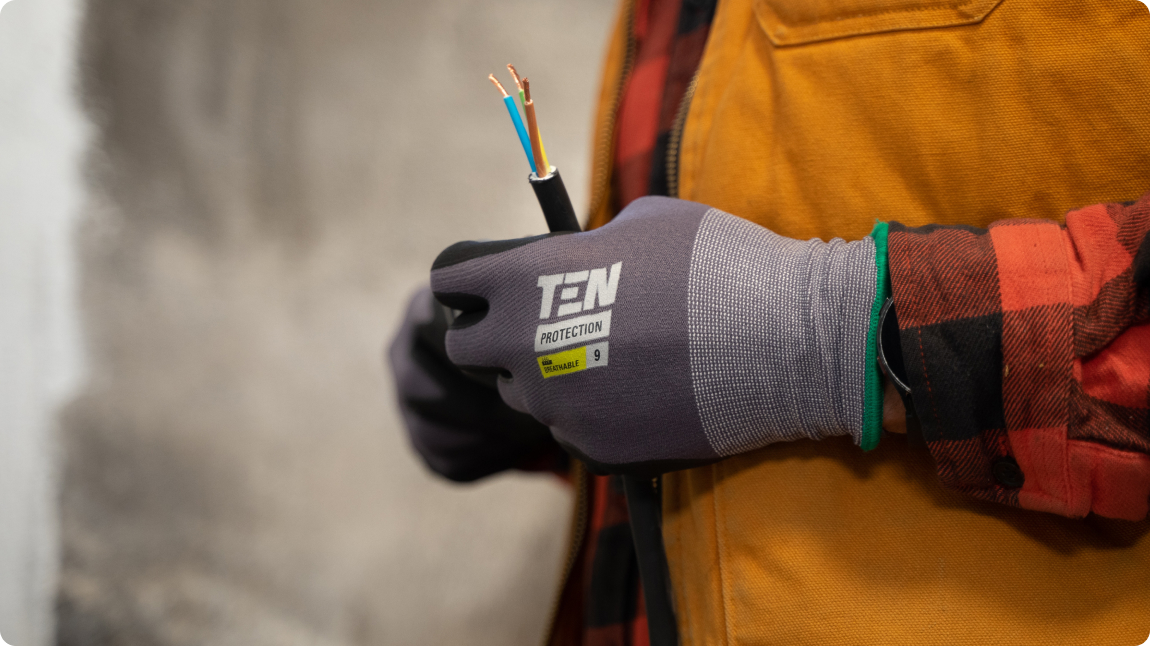 A person wearing protective gloves holding electrical wires