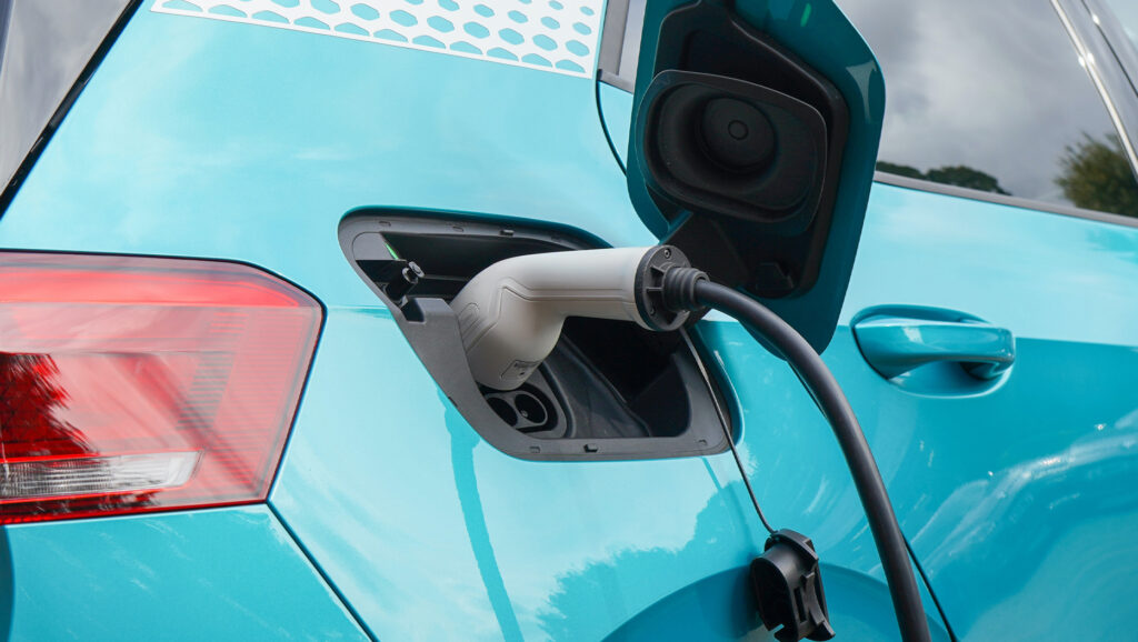Blue electric vehicle with charging cable plugging in