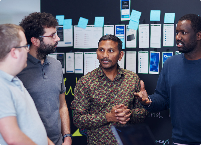 Team of people in discussion in front of a wall with post it notes