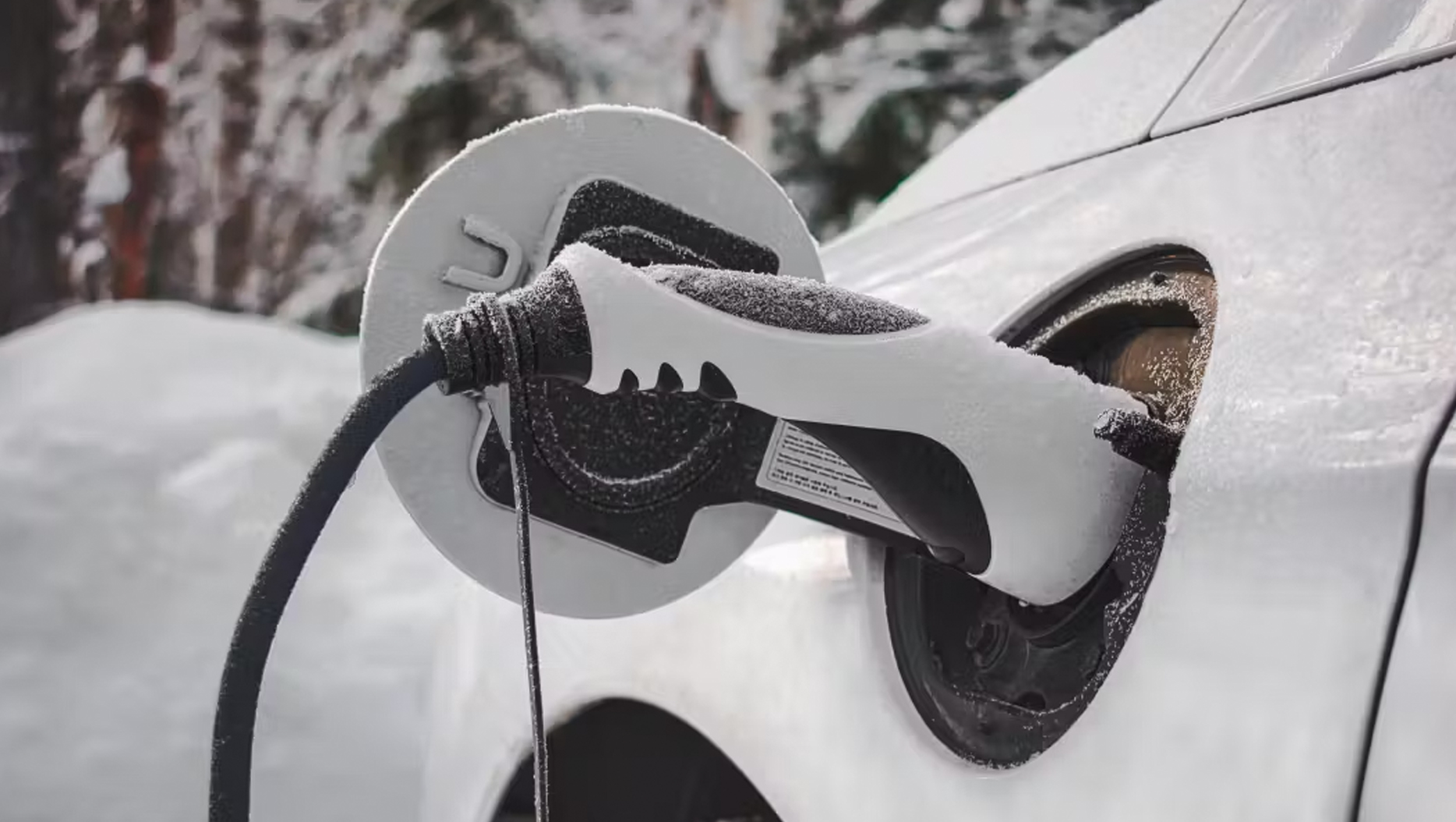 EV charge lead plugged into white car in snow