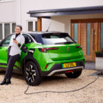 Green Mokka Electric, lady leaning on car charging her EV