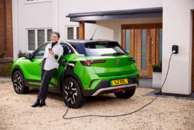 Green Mokka Electric, lady leaning on car charging her EV