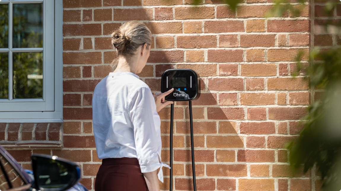 Woman using Ohme Home Pro on a red brick wall