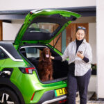 Green Vauxhall Mokka EV being charged with lady and red setter
