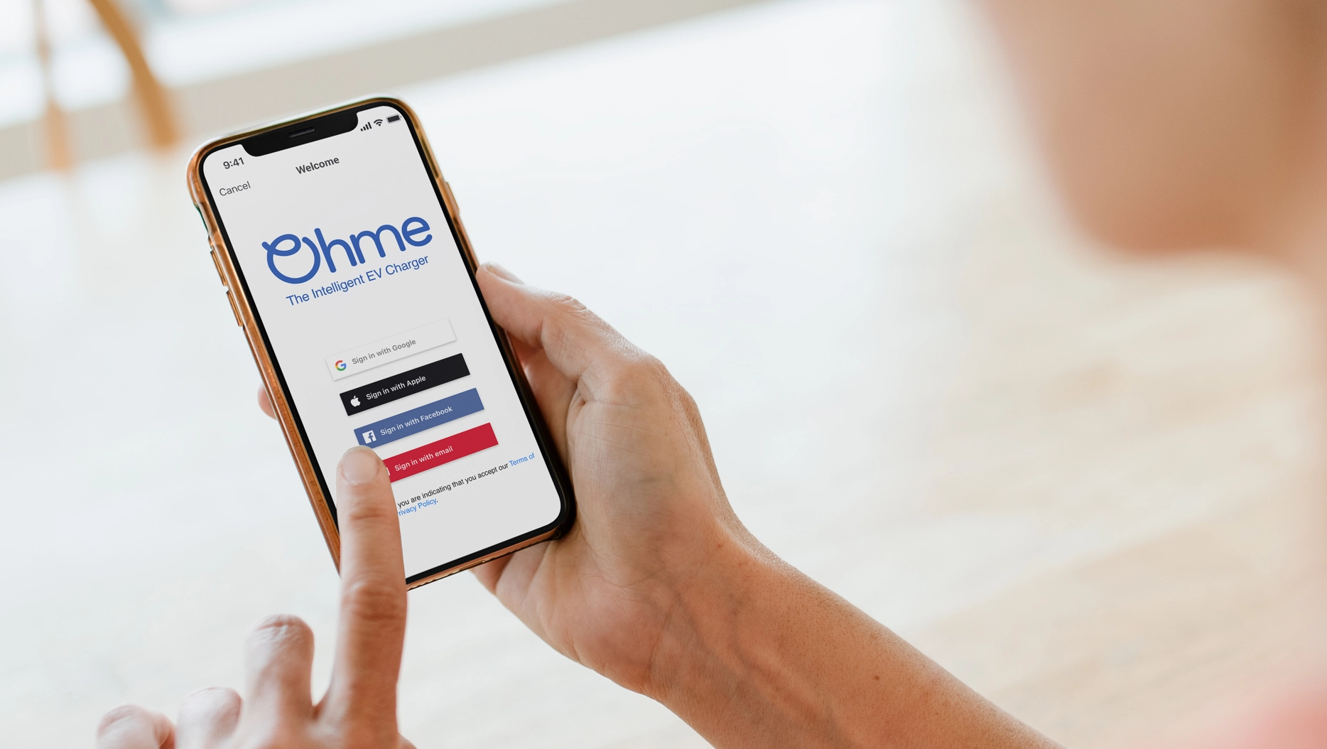 Person holding phone with Ohme app account options showing