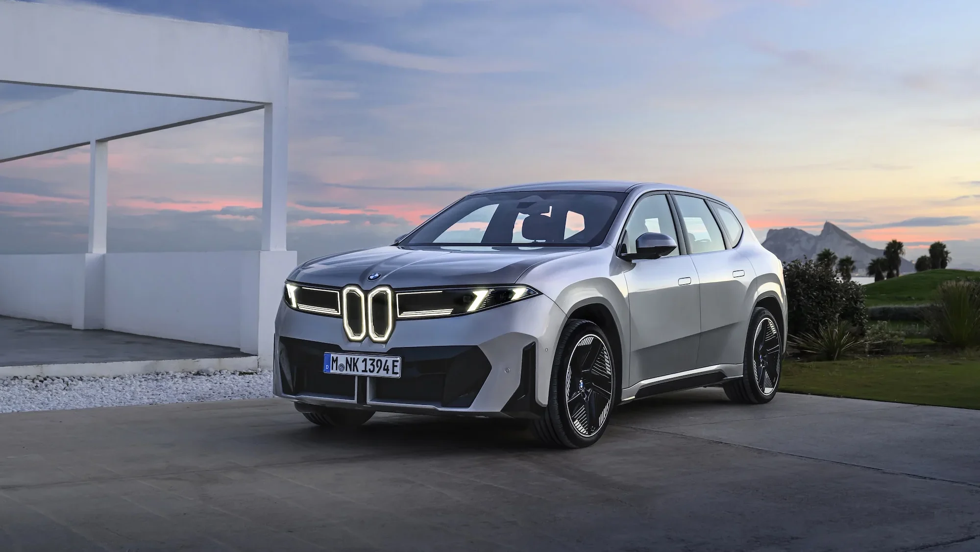 Silver BMW iX3 parked at sunset