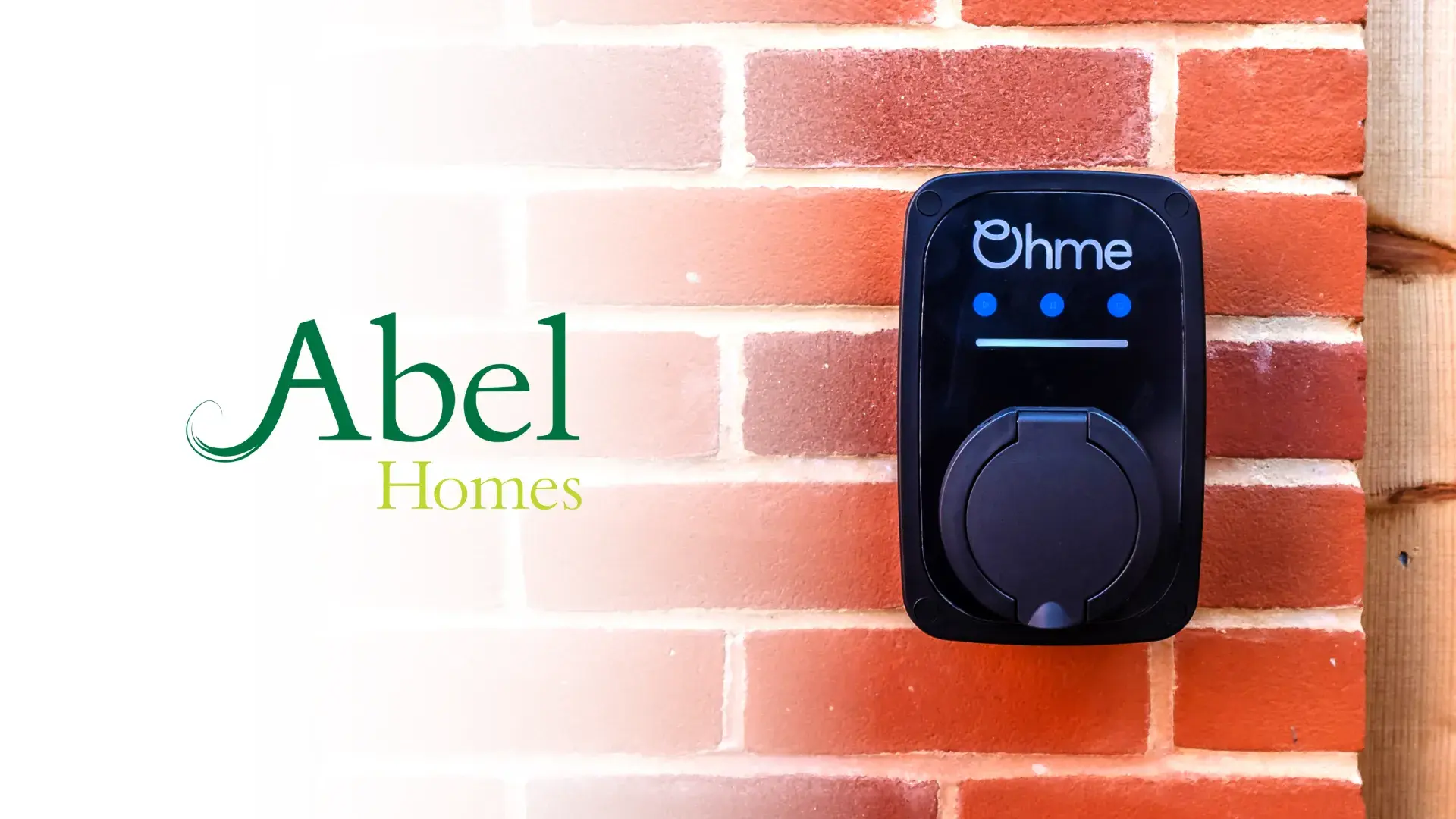 Ohme charger on red brick wall next to imposed Abel Homes logo